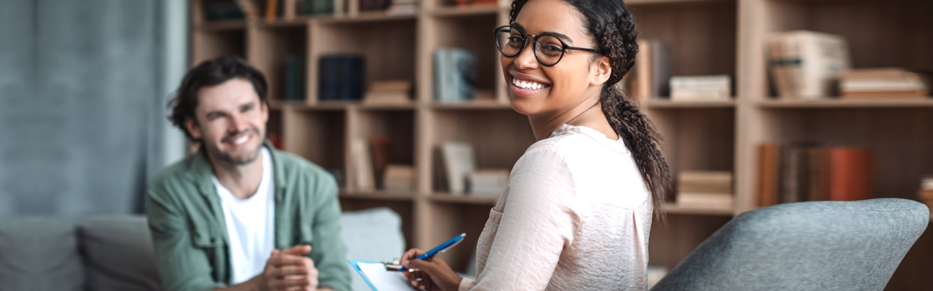 psychologist in glasses look at camera, consulting smiling european man in office clinic interior